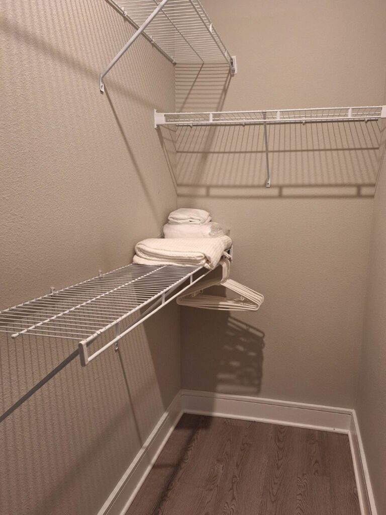 Spacious walk-in closet at Vale Apartments featuring built-in shelving, hanging racks, storage space, and room for extended stay luggage and personal belongings.