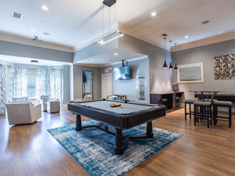 Resident clubhouse at Waterstone at Brier Creek featuring a billiards table, lounge seating, high-top gathering areas, entertainment space, and modern upscale finishes.
