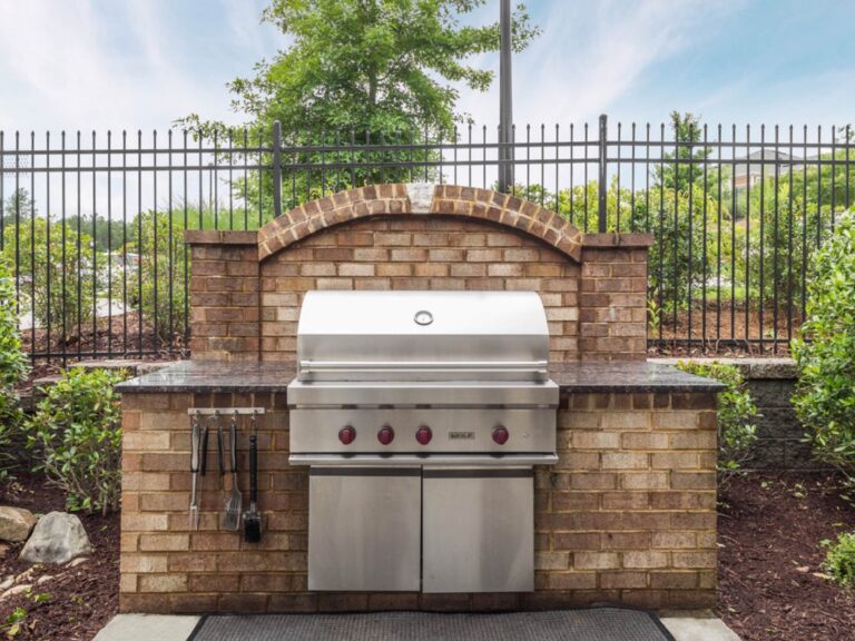 Community outdoor grilling station at Waterstone at Brier Creek featuring a built-in stainless steel gas grill, granite prep surfaces, and landscaped surroundings.