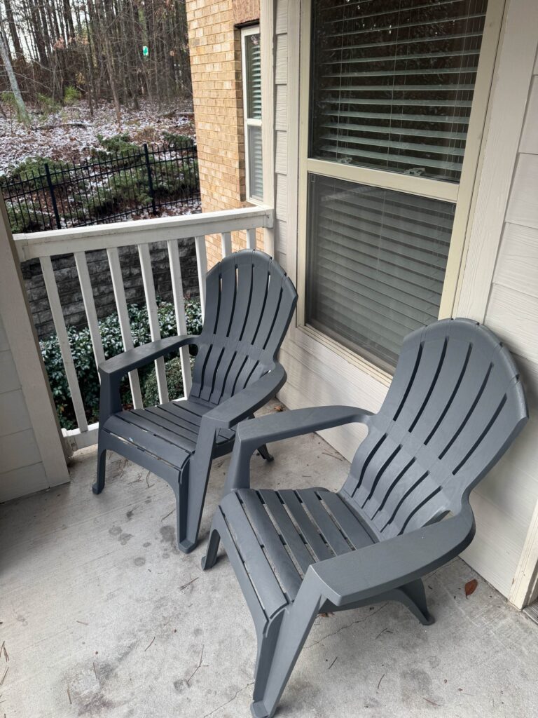Private covered patio featuring two outdoor Adirondack-style chairs overlooking landscaped grounds at Waterstone at Brier Creek in Lexington, Kentucky.