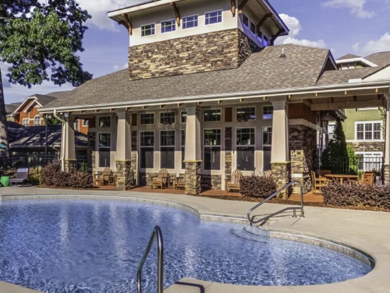 Resort-style swimming pool at Weirbridge Village featuring expansive sundeck space, comfortable seating areas, and a beautifully designed clubhouse with mountain-inspired architecture.