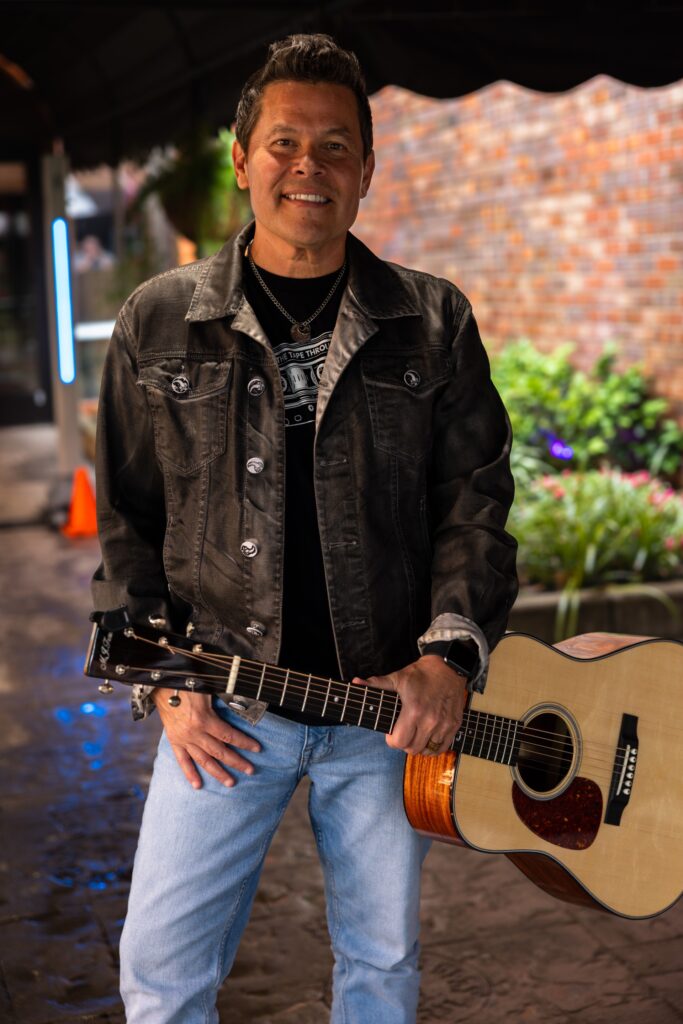 Jamie Johnson standing with an acoustic guitar in Nashville, representing Business Development at Luxury Corporate Lodging