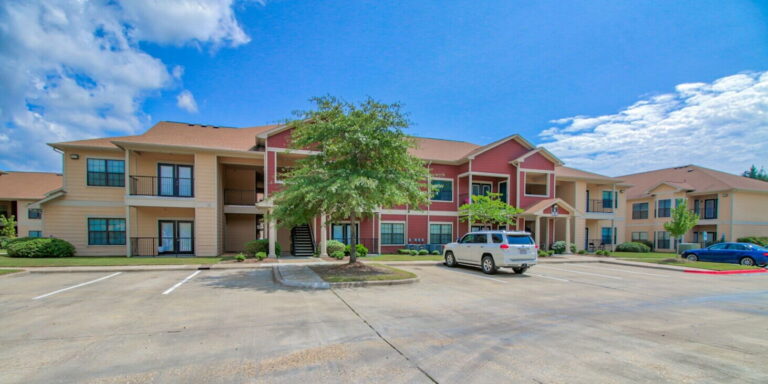 Exterior view of Vista Ridge Apartments in Tupelo, Mississippi, featuring apartment buildings, landscaped grounds, ample parking, and residential community amenities.