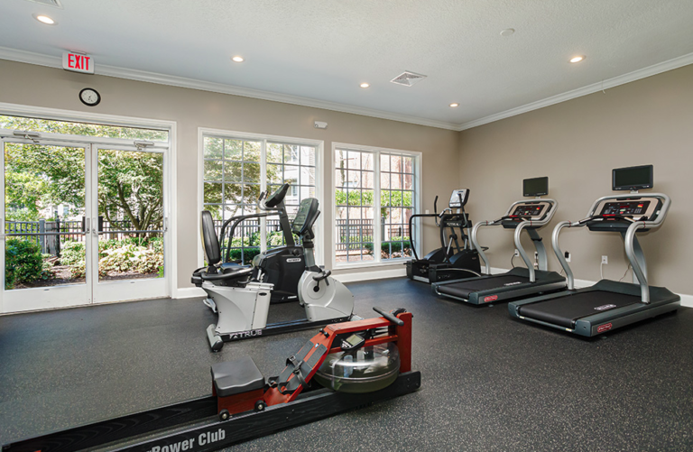 Modern fitness center at Waterford Crossing in Nashville featuring treadmills, cardio equipment, exercise bikes, rowing machine, large windows, and bright natural light.