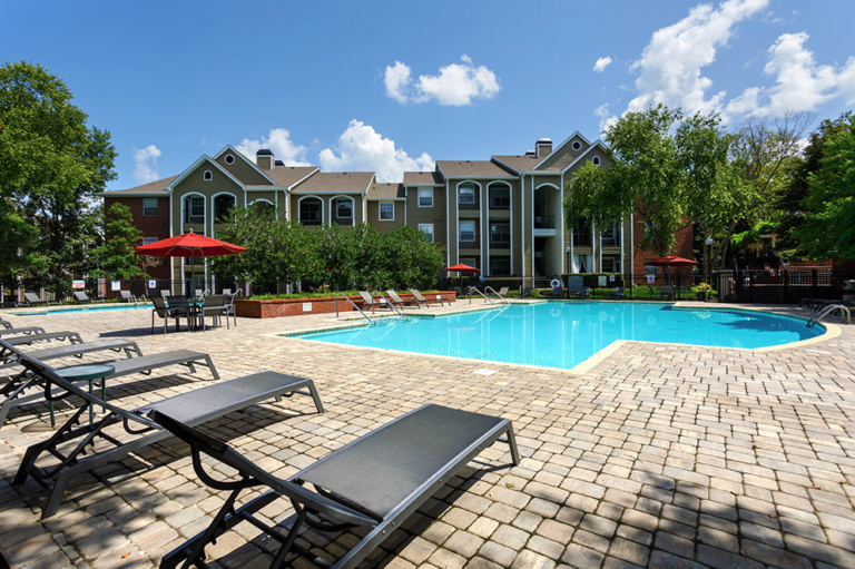 Resort-style community swimming pool at Waterford Crossing in Nashville featuring expansive sundeck seating, lounge chairs, umbrella tables, and beautifully landscaped surroundings.