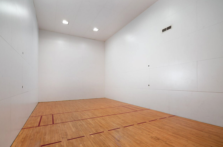 Indoor racquetball court at Waterford Crossing in Nashville featuring hardwood flooring, high ceilings, professional court markings, and bright overhead lighting.