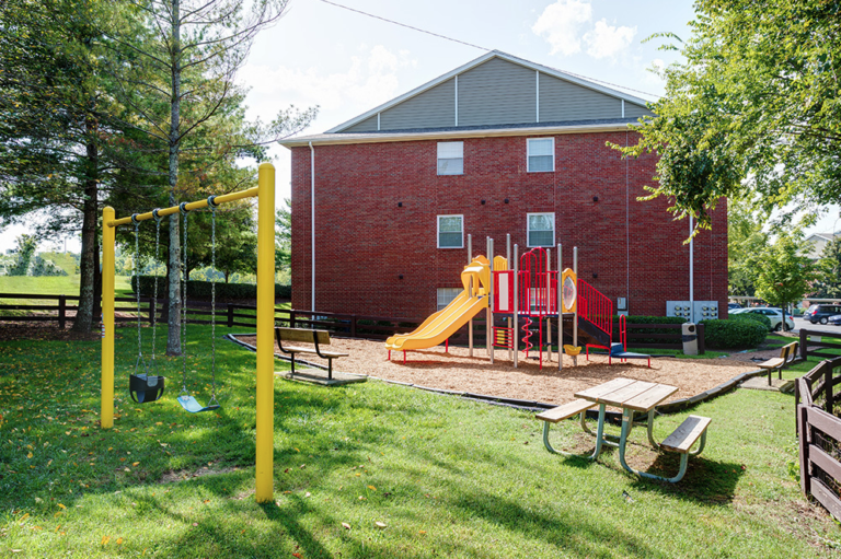 Family-friendly playground at Waterford Crossing in Nashville featuring swings, slides, climbing equipment, picnic tables, and open green space.