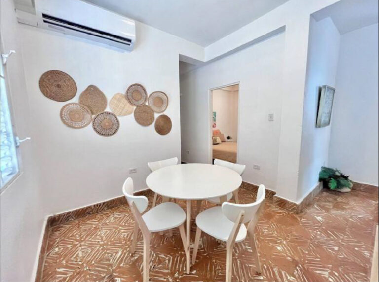 Modern dining room with round table, seating for four, and decorative wall accents.