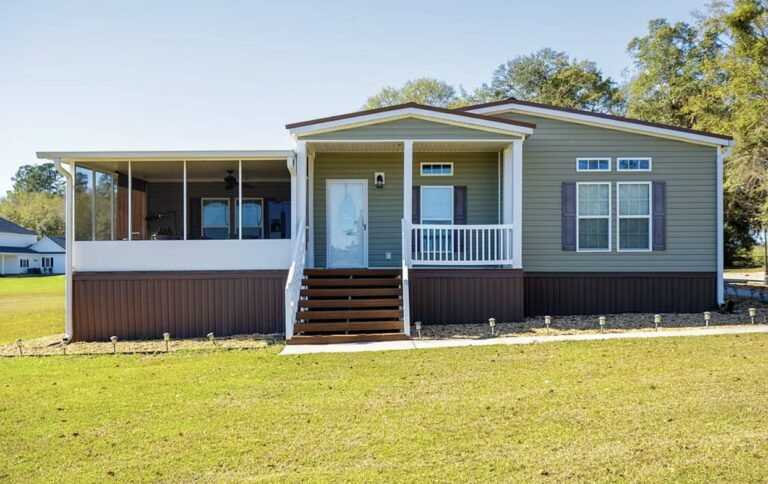 Front exterior view of a spacious single-story retreat home featuring a covered front porch, screened-in outdoor living area, and expansive lawn.