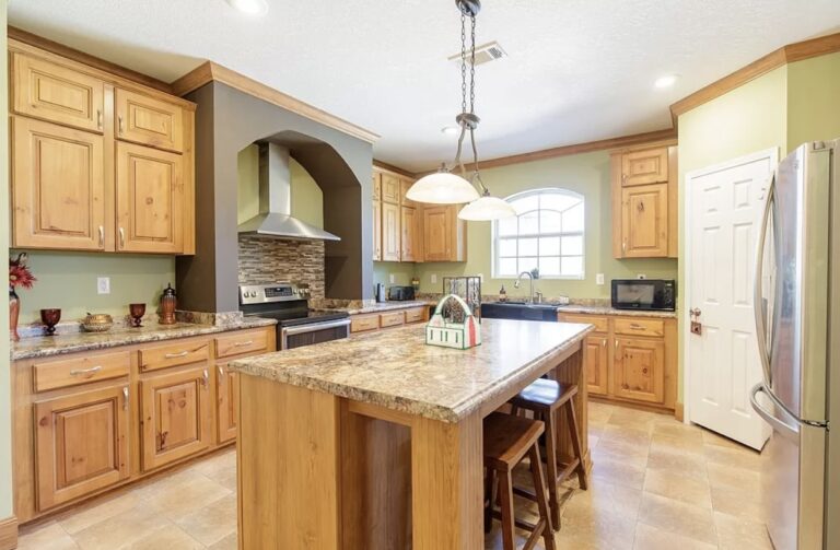 Large gourmet kitchen with granite island, natural wood cabinetry, stainless steel appliances, and seating for casual dining.