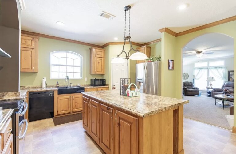 Spacious kitchen with granite island, custom wood cabinetry, stainless steel appliances, and open-concept design.