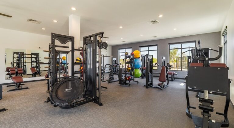 Modern fitness center at Solwyn Santa Fe featuring strength training equipment, functional fitness stations, free weights, and large windows with natural light.